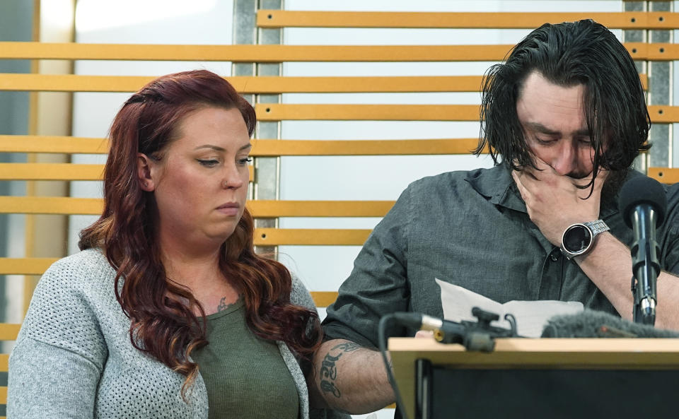 FILE - Jessica Vestal, right, consoles her husband, Devon, as he speaks during a news conference to announce plans to sue the Littleton, Colo., school district for abuse suffered by their autistic children while riding the bus to class, April 9, 2024, in Denver. Kiarra Jones, a school bus aide shown on surveillance video hitting a non-verbal autistic boy, has been charged with 10 more counts of abuse involving two children, prosecutors said Friday, May 3. Vestal’s son is one of two children that Jones is charged with abusing, according to Vestal’s attorney. (AP Photo/David Zalubowski, File)