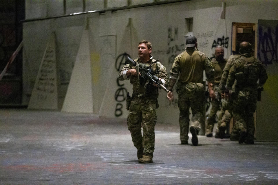 Federal officers pull a protester into the Federal Courthouse as Portland protesters gather downtown on Friday, July 10, 2020. (Dave Killen/The Oregonian via AP)