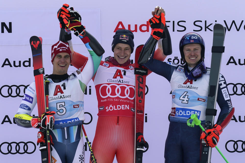 Switzerland's Marco Odermatt, centre, the winner, Slovenia's Zan Kranjec, left, second placed, and Norway's Henrik Kristoffersen, third, celebrate after an alpine ski, men's World Cup giant slalom, in Soelden, Austria, Sunday, Oct. 23, 2022. (AP Photo/Giovanni Auletta)
