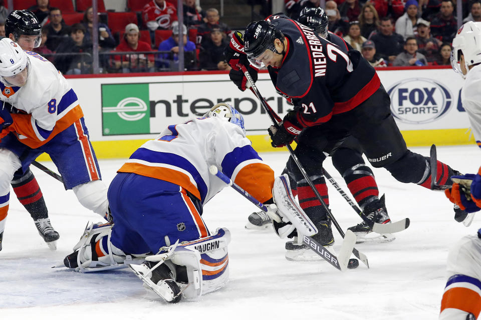 Carolina Hurricanes' Nino Niederreiter (21), of Switzerland, tries to control the puck in front of New York Islanders goaltender Thomas Greiss (1), of Germany, during the first period of an NHL hockey game in Raleigh, N.C., Sunday, Jan. 19, 2020. (AP Photo/Karl B DeBlaker)