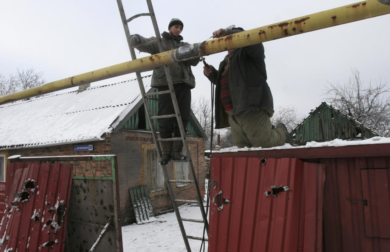 Men repair a gas pipeline outside a house which was damaged by shelling in Donetsk, eastern Ukraine, January 5, 2015. REUTERS/Igor Tkachenko (UKRAINE - Tags: POLITICS CIVIL UNREST CONFLICT)