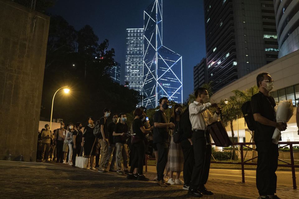 People wait in line to pay tribute to Queen Elizabeth II outside the British Consulate in Hong Kong, Friday, Sept. 16, 2022. Hundreds of Hong Kong residents are lining up in front of the British Consulate General for hours each day to pay their respects to Queen Elizabeth II, leaving piles of flowers and handwritten notes. (AP Photo/Anthony Kwan)