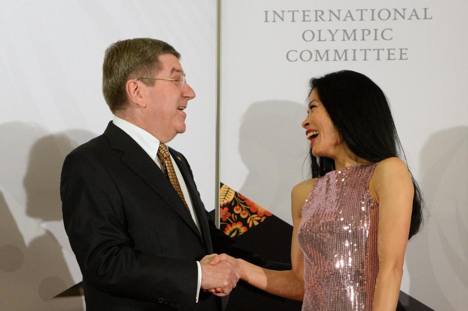In this photo taken on Thursday, Feb. 6, 2014, International Olympic Committee President Thomas Bach, left, shares a laugh with former musician Vanessa-Mae, who will compete for Thailand as alpine skier Vanessa Vanakorn before the IOC President's Gala Dinner on the eve of the opening ceremony of the 2014 Winter Olympics, in Sochi, Russia. As a violin virtuoso, Vanessa-Mae has been endearing herself to large audiences since she was a small child. Because of her flourishing musical career, skiing has played always second fiddle. At the Sochi Winter Games, that tune will change. The classical-pop musician is set to compete for Thailand in the Olympic giant slalom on Tuesday, Feb. 18. (AP Photo/Andrej Isakovic, Pool)