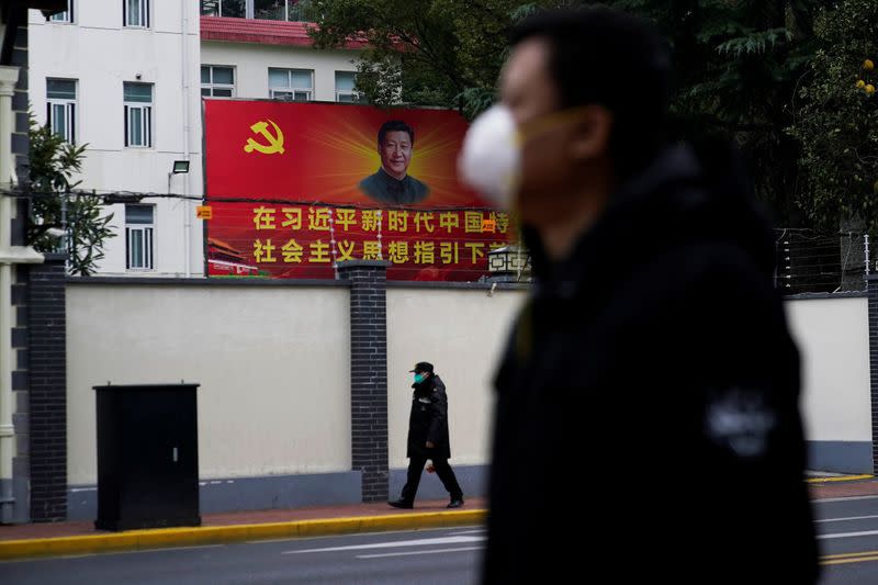 People wearing masks walk past a portrait of Chinese President Xi Jinping on a street as the country is hit by an outbreak of the novel coronavirus in Shanghai