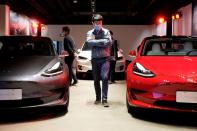 FILE PHOTO: FILE PHOTO: Man walks by Tesla Model 3 sedans and Tesla Model X sport utility vehicle at a new Tesla showroom in Shanghai