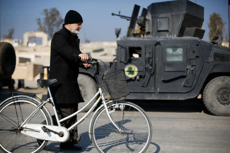 A civilian walks next to a vehicle of the Iraqi Special Operations Forces (ISOF) as he leaves the city to escape from clashes during a battle with Islamic State militants, in al-Zirai district in Mosul, Iraq, January 19, 2017. REUTERS/Muhammad Hamed