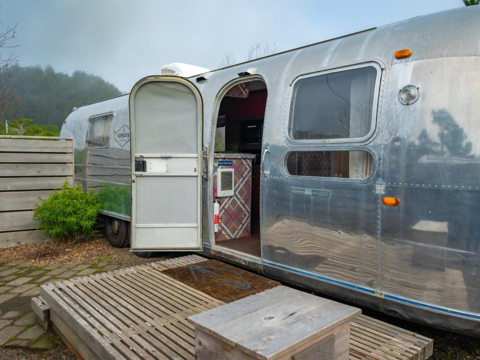 airstream with door open onto wooden deck area