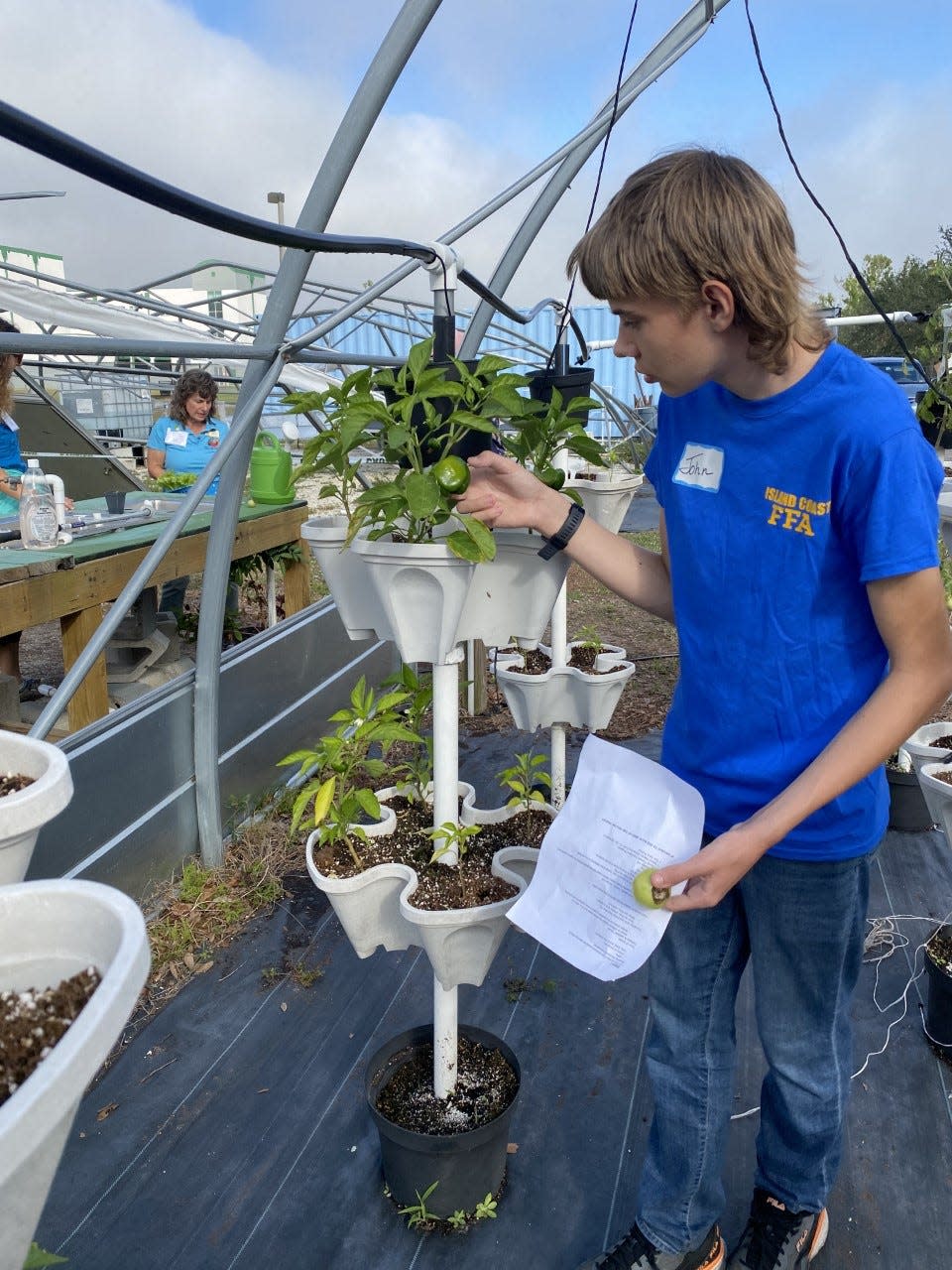 Island Coast High School student and Academy of Natural Resources member John Bowers checks out a bell pepper plant in the school's garden.