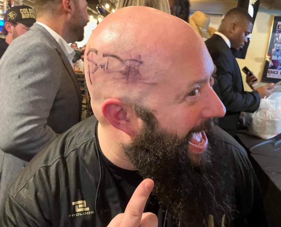A restaurant worker at Peckish in Boulder shows off the autograph on his head from Colorado quarterback Shedeur Sanders at a pop-up event in Boulder, Colorado,