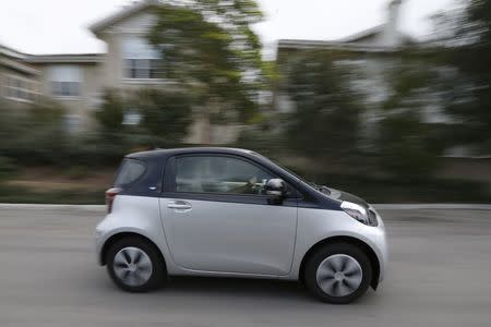 A Scion IQ electric car given to a resident of University of California, Irvine faculty housing drives down a street in Irvine, California January 26, 2015. REUTERS/Lucy Nicholson