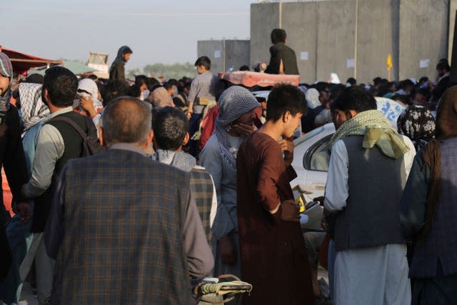 Hundreds of people gather near an evacuation control checkpoint during ongoing evacuations at Hamid Karzai International Airport