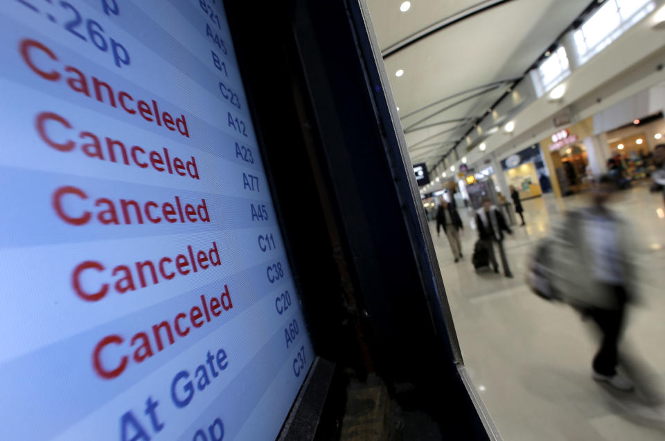 Travelers on Delta Airlines look at a departure screen Monday, Oct. 29, 2012, in Detroit. Dozens of departing flights have been canceled at Detroit Metropolitan Wayne County Airport as a looming superstorm locks down flights to the East Coast. Hurricane Sandy continued on its path Monday, as the storm forced the shutdown of mass transit, schools and financial markets, sending coastal residents fleeing, and threatening a dangerous mix of high winds and soaking rain. (AP Photo/Charlie Riedel)