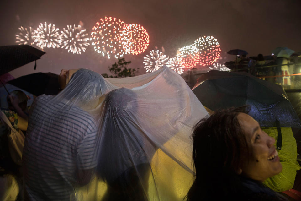 <p>A couple braves heavy rain to watch fireworks set off to mark the 20th anniversary of the Hong Kong handover to China in Hong Kong, Saturday, July 1, 2017. (Photo: Ng Han Guan/AP) </p>