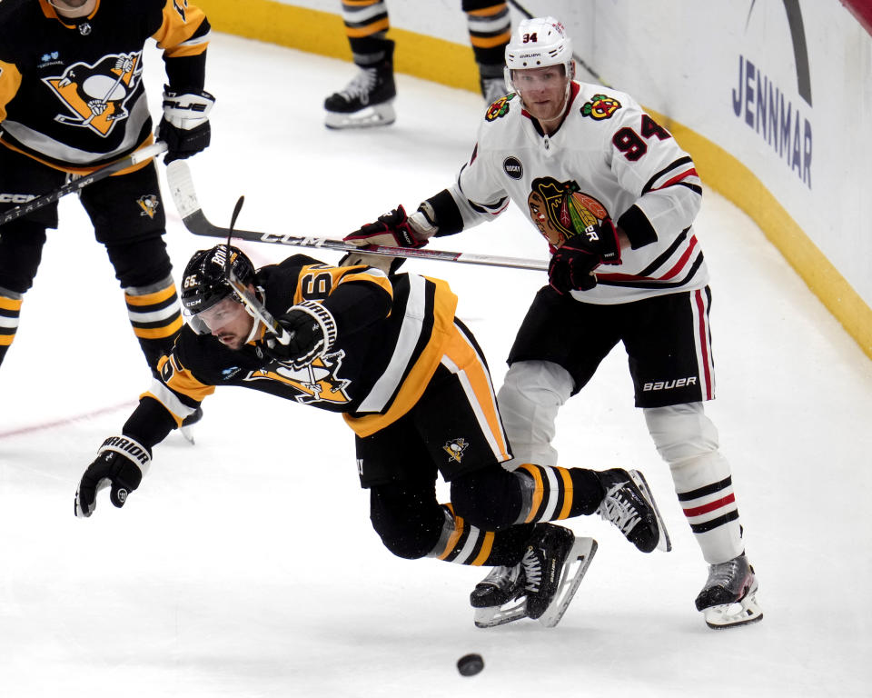 Chicago Blackhawks' Corey Perry (94) checks Pittsburgh Penguins' Erik Karlsson (65) off the puck during the third period of an NHL hockey game in Pittsburgh, Tuesday, Oct. 10, 2023. (AP Photo/Gene J. Puskar)