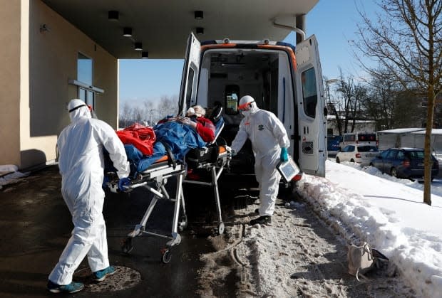 Medical workers move a COVID-19 patient into an ambulance at a hospital overrun by the disease in Cheb, Czech Republic, on Feb. 12. The small city near the German border has a death rate six times the national average.