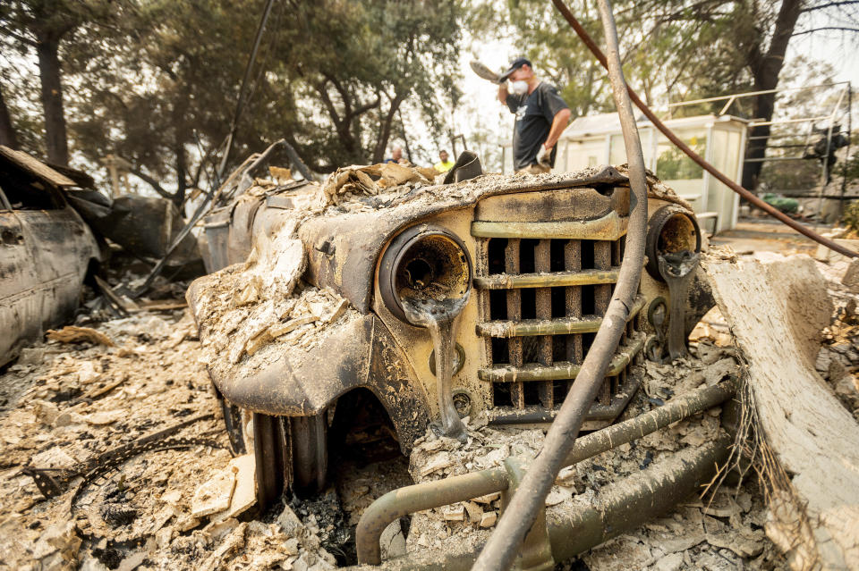 Mark Hanson goes through the remains of a 1951 Willys-Overland Jeepster following the LNU Lightning Complex fires in Vacaville, Calif., on Friday, Aug. 21, 2020. The blaze destroyed his family home as well as the Jeepster which his father purchased new and Mark rebuilt while in high school. (AP Photo/Noah Berger)