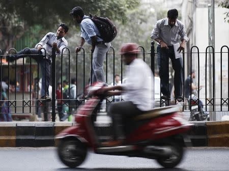 Pedestrians climb a fence on a road divider to cross a busy road in New Delhi October 28, 2014. REUTERS/Anindito Mukherjee