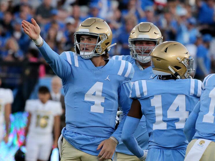 UCLA quarterback Ethan Garbers signals a first down after scrambling in front of fans at the Rose Bowl