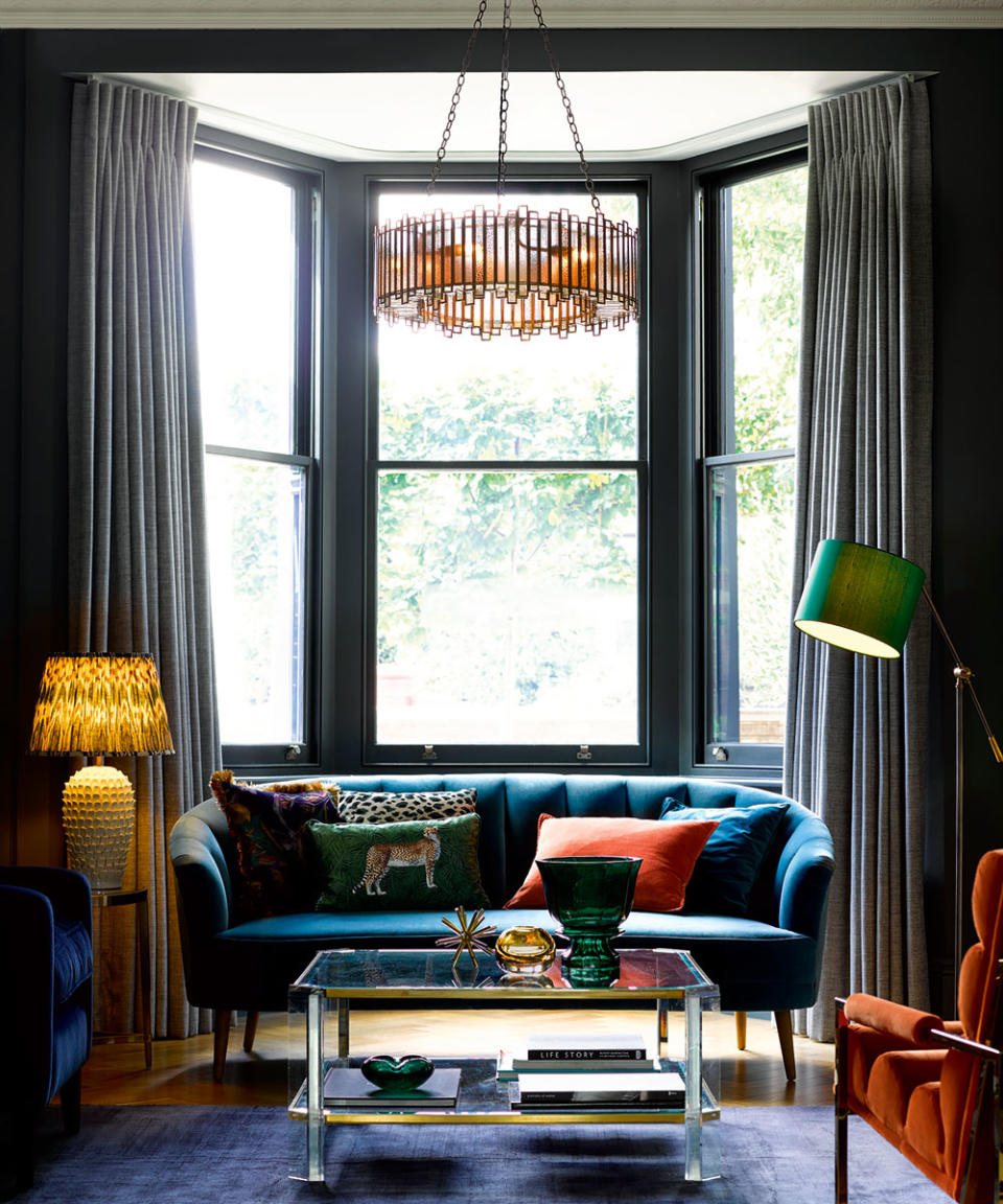 Living room with large bay windows, blue sofa and statement chandelier