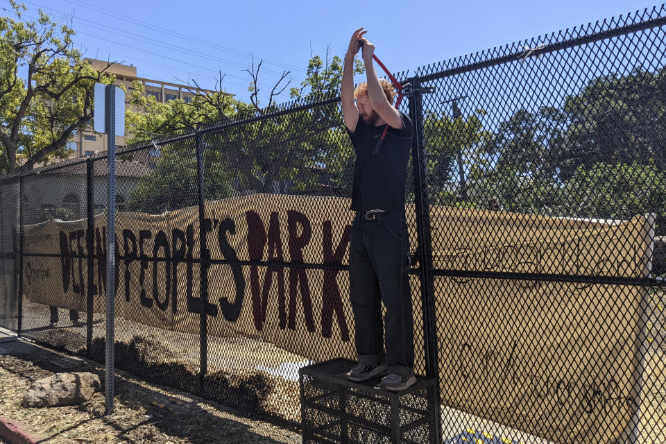 FILE - A protester uses bolt cutters to take down part of the fence that the University of California, Berkeley, erected around historic People's Park, Aug. 3, 2022, so a construction crew could begin work on a long-planned student housing project in Berkeley, Calif. A California Supreme Court ruling will allow student housing at University of California to be built at Berkeley's historic People's Park. (AP Photo/Michael Liedtke, File)