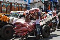 Laborers carry sacks of food grains at a market area in Kolkata, India, Thursday, Sept. 3, 2020. India has registered a record single-day spike of 83,883 new coronavirus cases, driving the country overall tally to 3.85 million. The country has been reporting the highest single-day caseload in the world every day for more than three weeks and is the third worst-hit country behind the United States and Brazil. (AP Photo/Bikas Das)