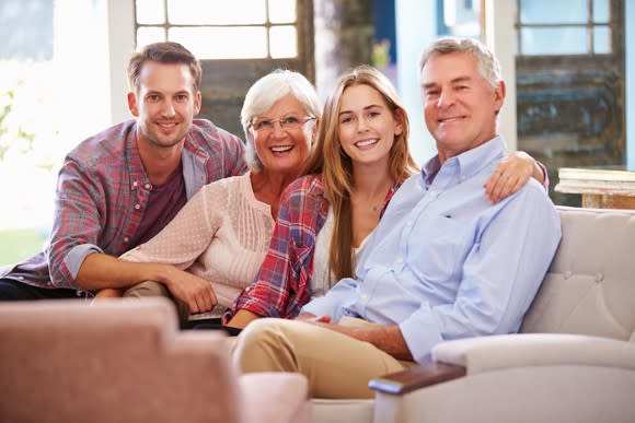 Older parents sitting on a couch with their two adult children