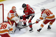 Calgary Flames goalie Jacob Markstrom (25) and teammate Andrew Mangiapane (88) battle Chicago Blackhawks' Nick Foligno (17) for a loose puck during the first period of an NHL hockey game Tuesday, March 26, 2024, in Chicago. (AP Photo/Paul Beaty)