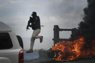 A police officer abandons his vehicle during a demonstration that turned violent in which protesters demanded justice for the assassinated President Jovenel Moise in Cap-Haitien, Haiti, Thursday, July 22, 2021. Demonstrations after a memorial service for Moise turned violent on Thursday afternoon with protesters shooting into the air, throwing rocks and overturning heavy concrete barricades next to the seashore as businesses closed and people took cover. (AP Photo/Matias Delacroix)