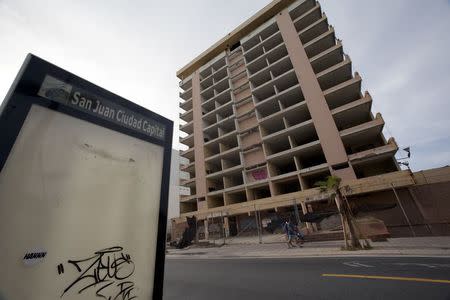 Pedestrians pass an abandoned hotel in the tourist area of San Juan, Puerto Rico, July 18, 2015. REUTERS/Alvin Baez