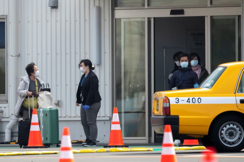 Passengers wearing masks leave the coronavirus-hit cruise ship Diamond Princess at Daikoku Pier Cruise Terminal in Yokohama