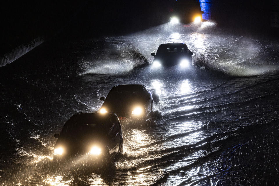 Vehicles drive through a flooded section of the A59 highway as heavy rain falls, Thursday evening, June 22, 2023, in Duisburg, Germany. (Christoph Reichwein/dpa via AP)