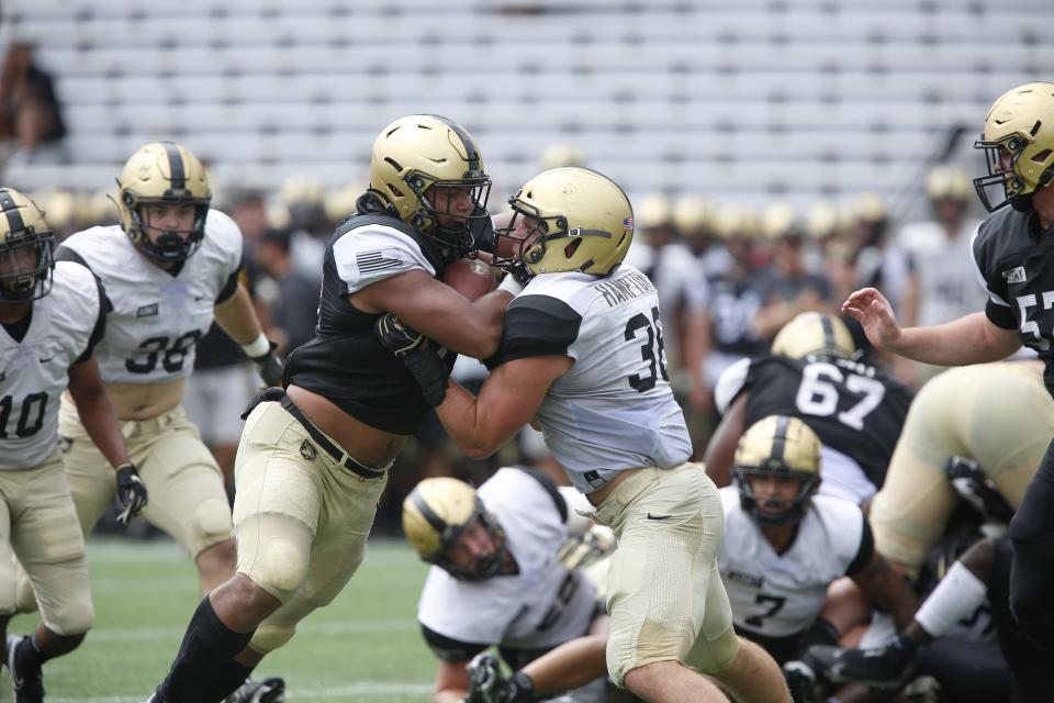 Army running back Tyson Riley (left) tries to drive through linebacker Peyton Hampton during Saturday's Army football scrimmage.