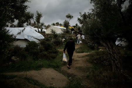 A refugee carries his lunch provided by the Greek authorities, at a makeshift camp for refugees and migrants next to the Moria camp on the island of Lesbos, Greece, November 30, 2017. REUTERS/Alkis Konstantinidis