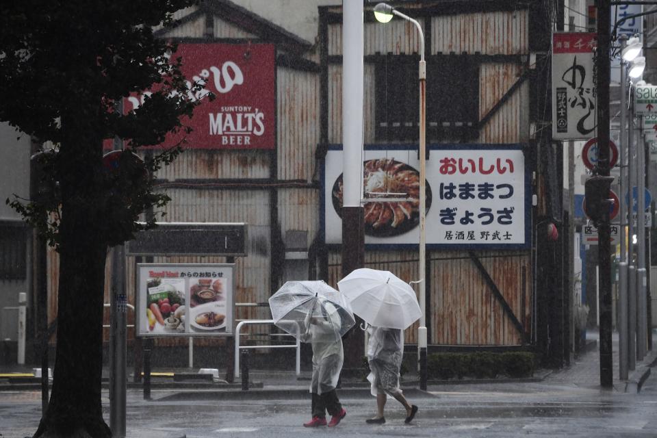 Pedestrians use umbrellas to shield themselves from the rain as they walk along a street in Hamamatsu, Shizuoka prefecture on October 12, 2019, as the country prepares for the landfall of Typhoon Hagibis. - Powerful typhoon Hagibis has made landfall in Japan, officials said on October 12, as torrential rain and winds have already lashed the country causing floods and mudslides. (Photo by Anne-Christine POUJOULAT / AFP) (Photo by ANNE-CHRISTINE POUJOULAT/AFP via Getty Images)