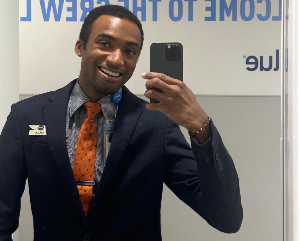 A man taking a selfie in a flight attendant uniform.