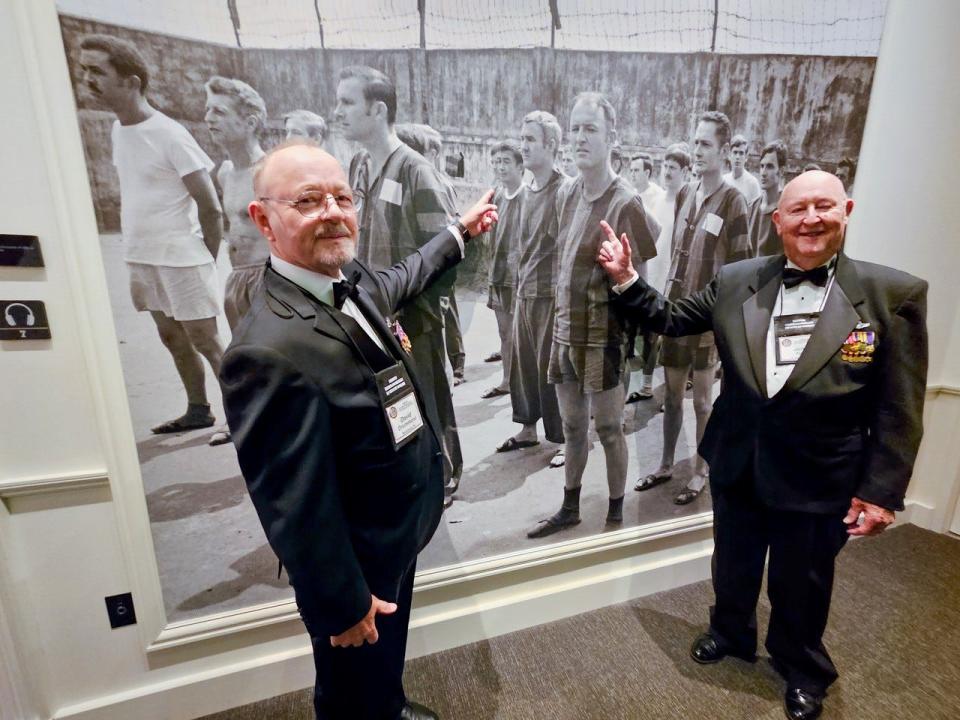 David Drummond, left, points to himself in a photo from 50 years earlier, when he was a prisoner of war in Vietnam. The photo was displayed at the Richard Nixon Presidential Library and Museum for a 50th reunion of the 4th Allied POW Wing in May 2023. At right is Drummond's fellow B-52 pilot, John Yuill.