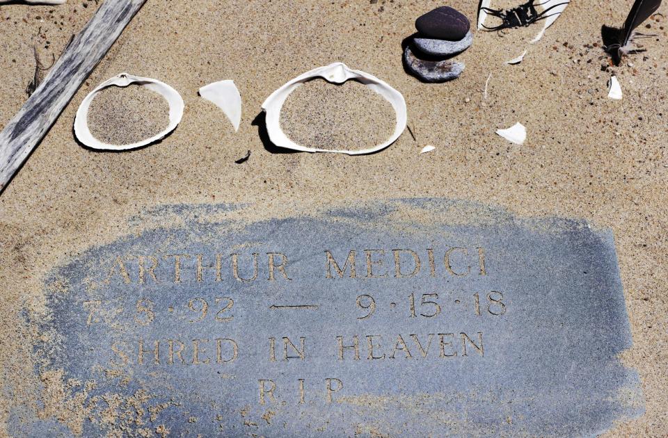 In the May 22, 2019, photo, a memorial stone for Arthur Medici, who died of injuries sustained in a shark attack while boogie boarding the previous summer, is adorned with a tiny cairn and seashells at Newcomb Hollow Beach in Wellfleet, Mass. Cape Cod beaches open this holiday weekend, just months after two shark attacks, one of which was fatal, rattled tourists, locals and officials. Some precautionary new measures, such as emergency call boxes, have yet to be installed along beaches where great whites are known to frequent. (AP Photo/Charles Krupa)