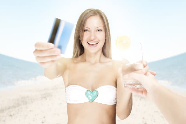 attractive young woman on the beach , paying for a cocktail with credit card