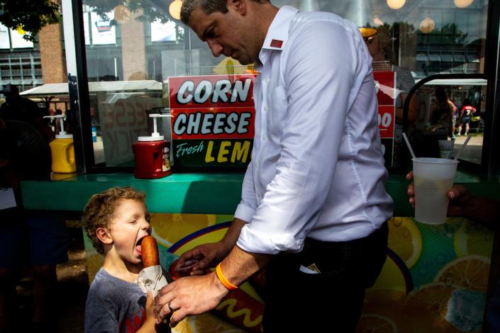 U.S. Rep. Tim Ryan, D-Ohio, hands his son Brady a corn dog while exploring the Iowa State Fair on Saturday, Aug. 10, 2019, in Des Moines. 