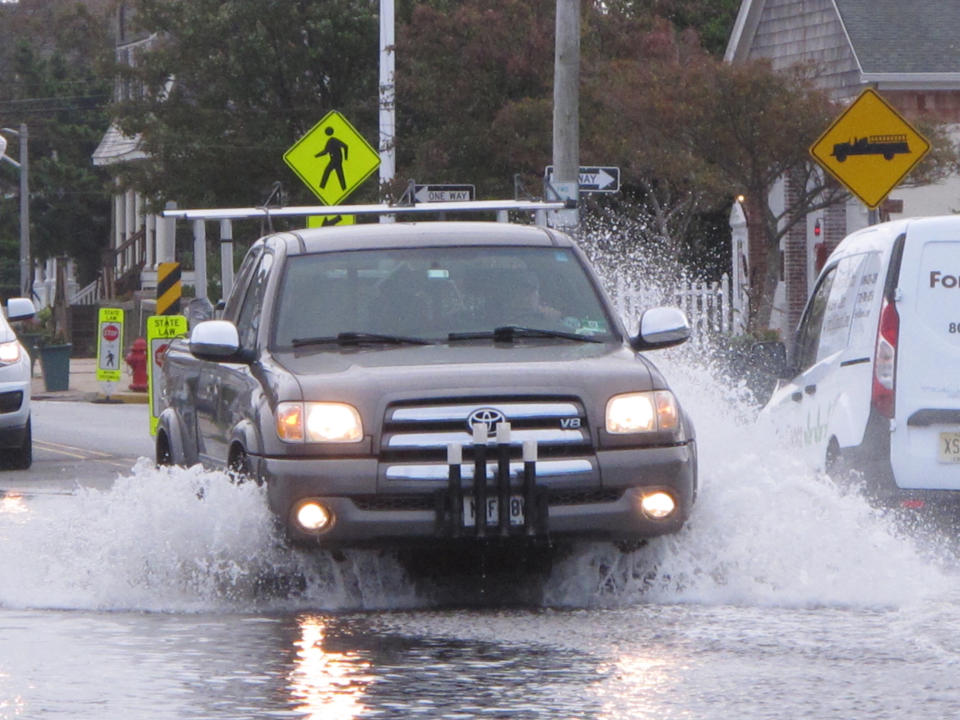 This Oct. 11, 2019, photo shows a car kicking up spray while driving through a flooded street in Bay Head, N.J. Bay Head is studying options to prevent, or at least reduce, incidents of so-called “sunny day” flooding caused by tides and rising sea levels, as well as major storm-related floods. New Jersey's Department of Environmental Protection and the U.S. Army Corps of Engineers have proposed a massive $16 billion plan to address back bay flooding along the shore. (AP Photo/Wayne Parry)