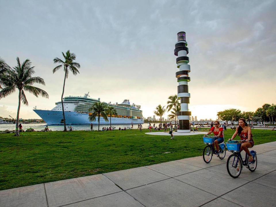 Two people bike down the sidewalk as Royal Caribbean International’s Freedom of the Seas cruise ship sets off down Government Cut past South Pointe Park for a simulated voyage leaving from PortMiami in Miami, Florida, on Sunday, June 20, 2021. In accordance with CDC requirements, the purpose of the simulation is to observe the cruise line’s multilayered health and safety measures.