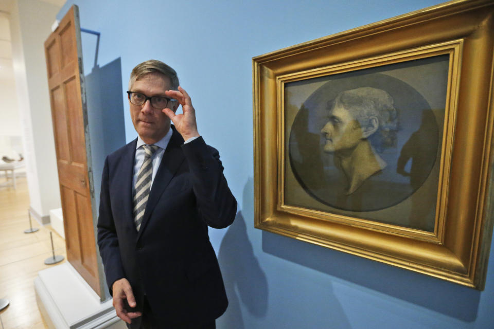 Erik H. Neil, director of the Chrysler Museum of Art, gestures next to a portrait of Jefferson during a tour of an exhibit titled "Thomas Jefferson, Architect: Palladian Models, Democratic Principles, and the Conflict of Ideals." At the museum in Norfolk, Va., Wednesday, Oct. 16, 2019. In the background is a door thought to be made by John Hemmings an enslaved woodworker and a brother of Sally Hemings, an enslaved woman whom scholars say had children with Jefferson. (AP Photo/Steve Helber)