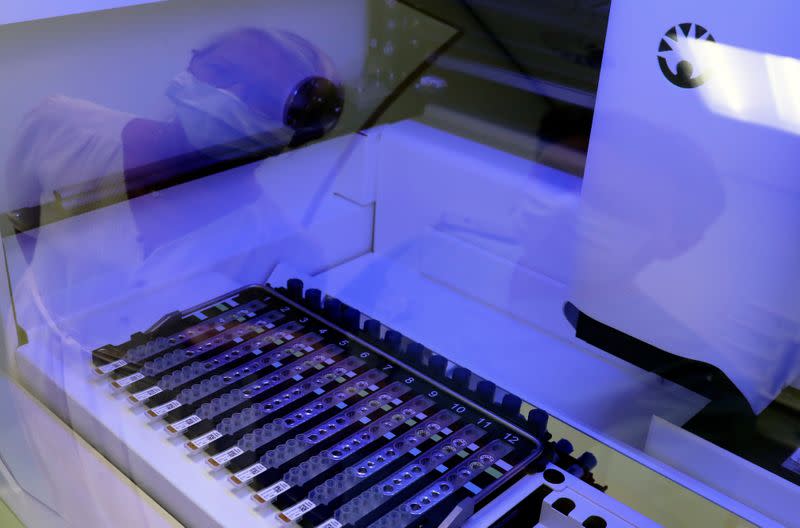 A laboratory worker is reflected in a glass as he checks the coronavirus disease (COVID-19) tests at the CHIREC Delta Hospital in Brussels