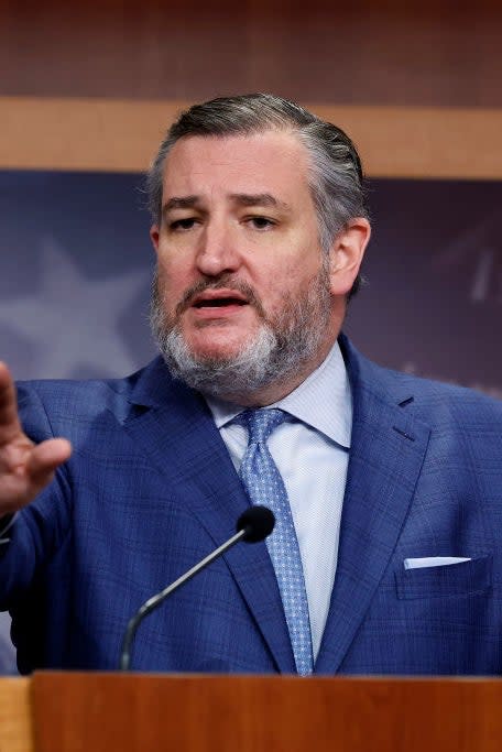 Ted Cruz speaking at a podium with a Capitol backdrop, wearing a suit and gesturing with his hand