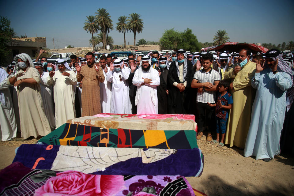 Mourners pray over the coffins of civilians killed by a Katyusha rocket attack near the international airport in Baghdad, Iraq, Tuesday, Sept. 29, 2020. Several Iraqi civilians were killed and two severely wounded Monday after the rocket hit near Baghdad airport, Iraq's military said. It was the first time in months an attack caused civilian casualties.(AP Photo/Khalid Mohammed)