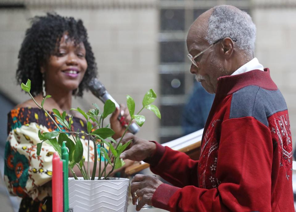 LaKesh Hayes, left, executive director of Project Ujima, watches as elder Thomas Smart Jr., 86, sprinkles water on a plant for a libation ceremony during the celebration Ujima, the principle celebrated on the third day of Kwanzaa signifying collective work and responsibility, at the Gus Johnson Community Center in Akron on Thursday. Kwanzaa is seven-day celebration of African-American culture from Dec. 26 to Jan. 1.