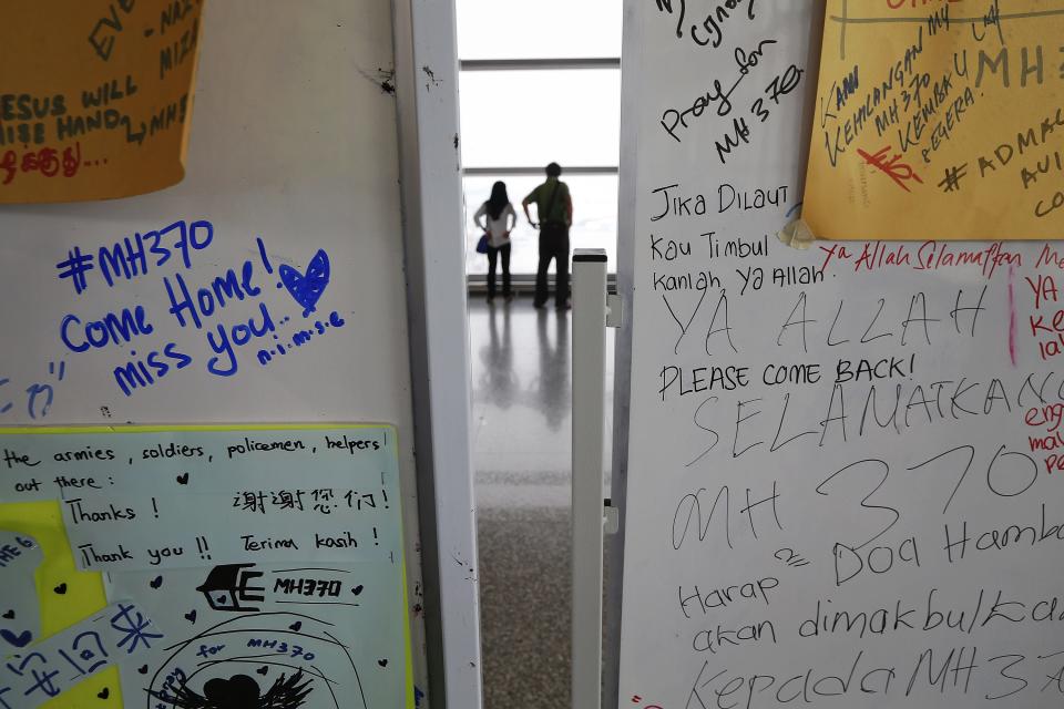 Una pareja mira los aviones en la pista de aterrizajes, detrás de las pizarras con mensajes de esperanza sobre los pasajeros abordo del avión MH370 de Malaysia Airlines en Kuala Lumpuren Malasia este 13 de marzo de 2014. REUTERS/Damir Sagolj