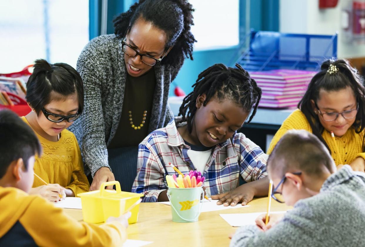 Year-round schooling can assist low-income parents in need of child care. <a href="https://www.gettyimages.com/detail/photo/teacher-helping-elementary-students-writing-in-royalty-free-image/1457744427" rel="nofollow noopener" target="_blank" data-ylk="slk:kali9/E+ Collection via Getty Images;elm:context_link;itc:0;sec:content-canvas" class="link ">kali9/E+ Collection via Getty Images</a>