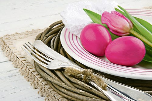 Easter dinner setting with two pink eggs and tulip, rustic white wooden background