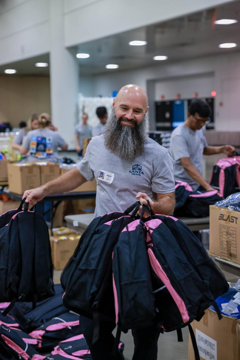 At a wrapping party for the CSX Santa Train in Jacksonville, employee Mario Zeni helps prepare gift-filled backpacks for the CSX Santa Train. Along the train's 110-mile route, another bearded gentleman, Santa Claus, will help deliver the backpacks to families in the Appalachian Mountains.